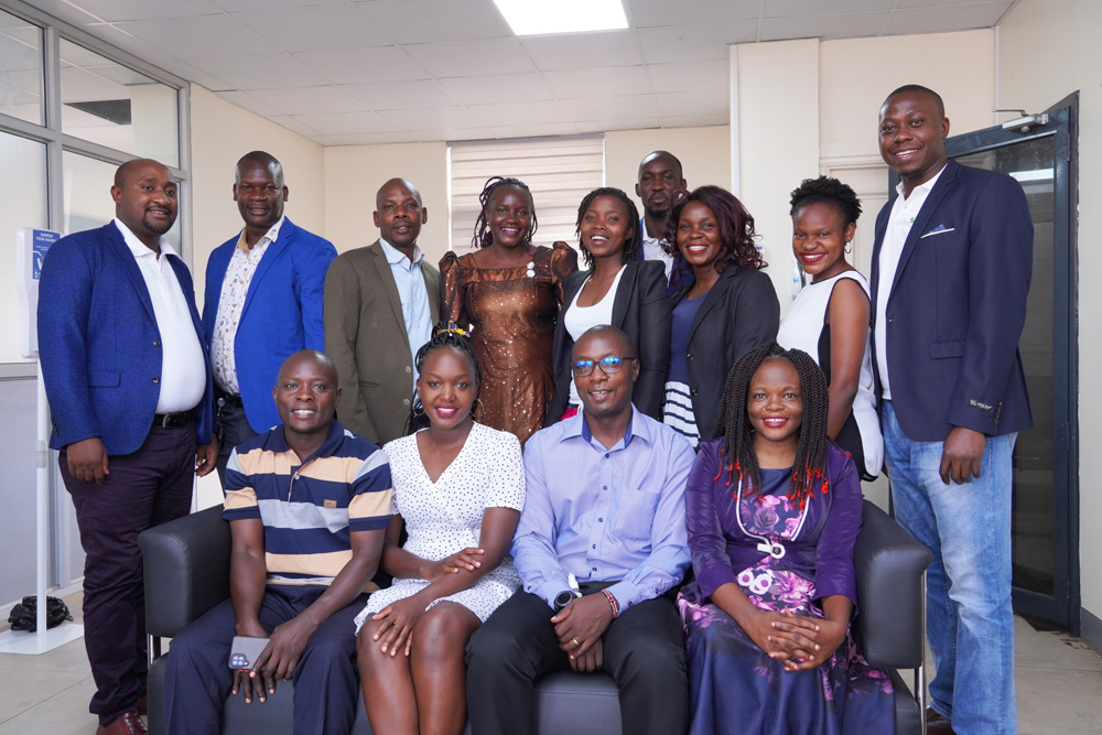 Photo of the staff at the Uganda office including Mr. Collins, sitting on the sofa.