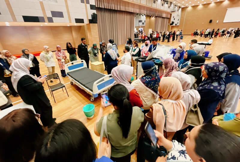 Attendees participating in lectures and practical training surroding a bed, awaiting for the lecture.